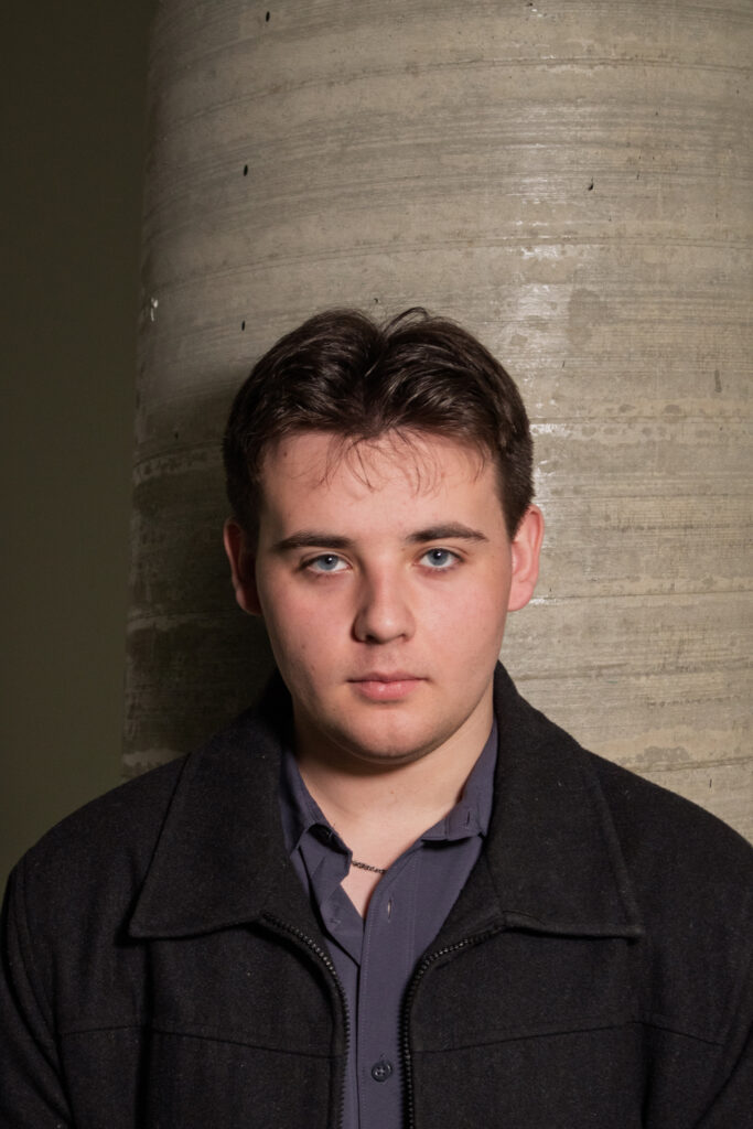 Max standing straight and confident in front of a large pillar, embodying what Amplora is all about—creativity, technical expertise, and growth. His posture conveys the stability and forward-thinking nature of the team.