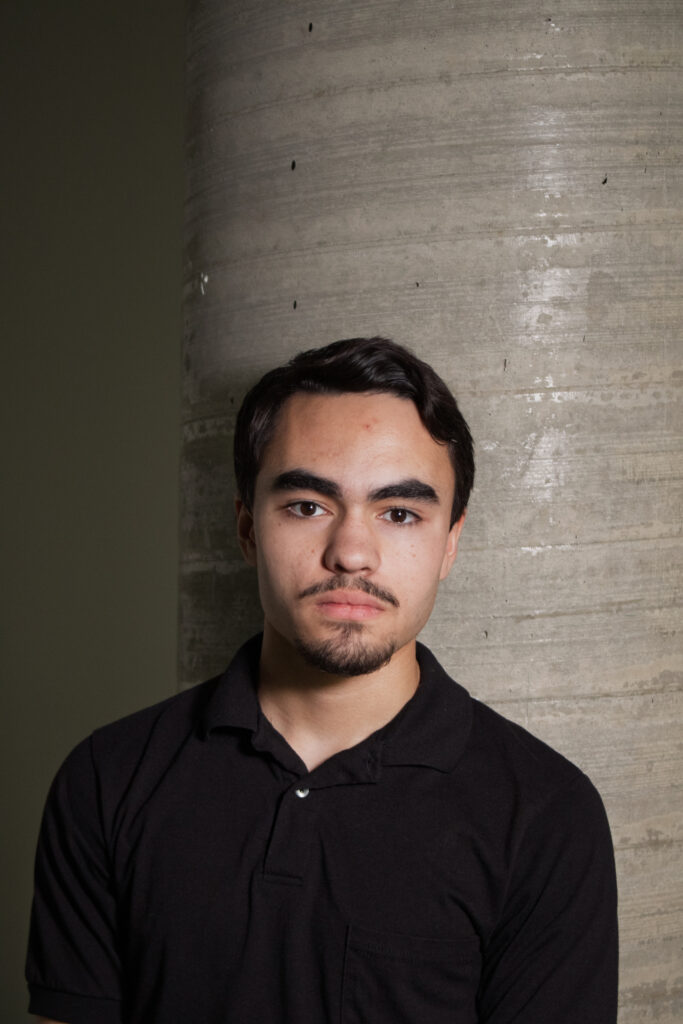 Elwood standing confidently in front of a large pillar, representing what Amplora is all about—professionalism, strength, and expertise. His presence symbolizes the foundation of the team, offering support and stability.
